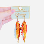Layered feather earrings in fall colors with plaid, glitter, textured leather, and gold chain accents.