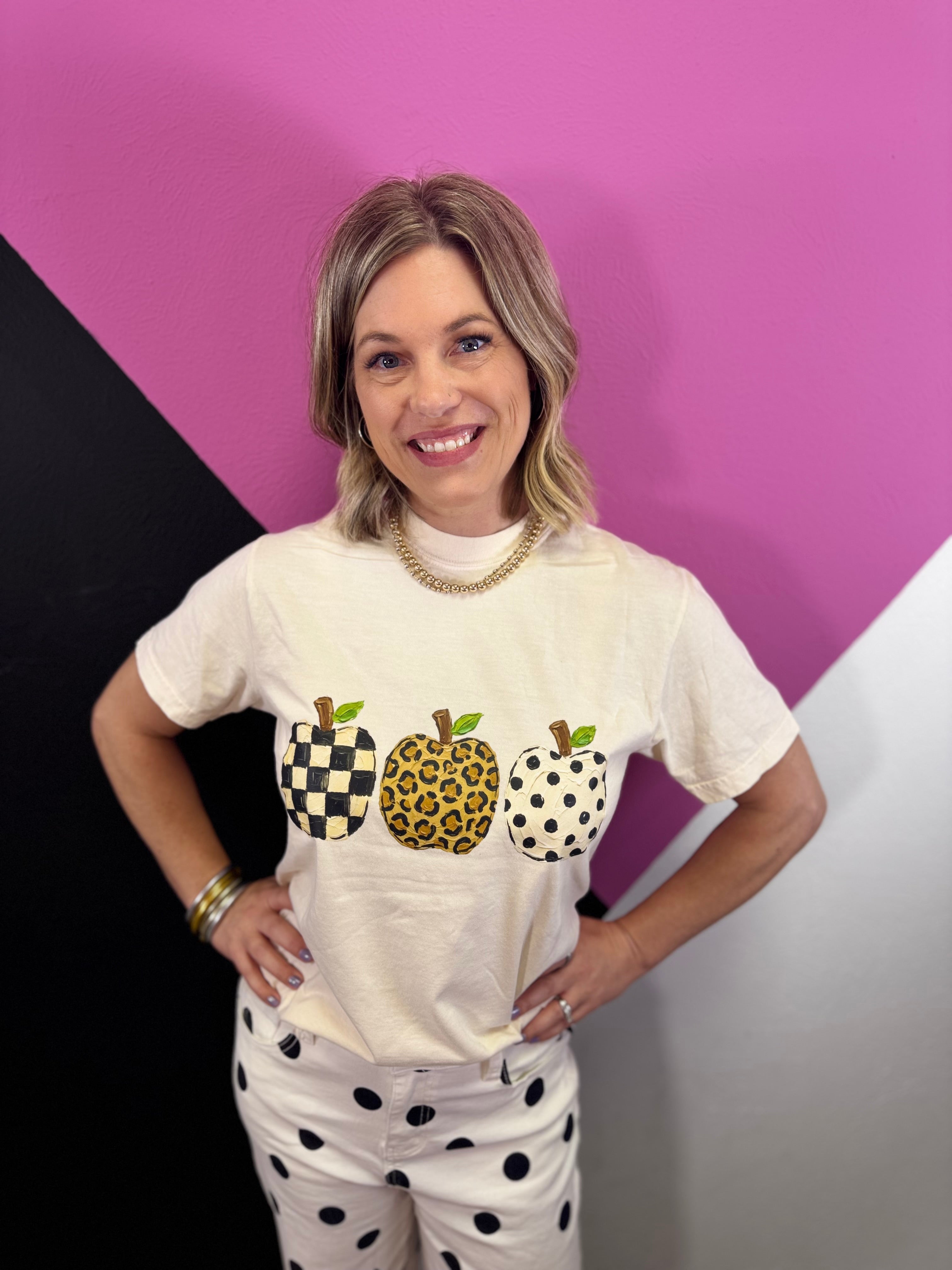 Graphic tee with three apples in leopard, checkered, and polka dot prints.