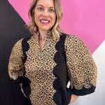 Leopard print top with black panels, scallop trim, and three-quarter puff sleeves