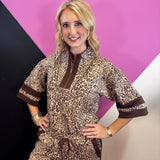 Leopard print pullover with rich brown contrast trim, zip neckline, and short wide sleeves.
