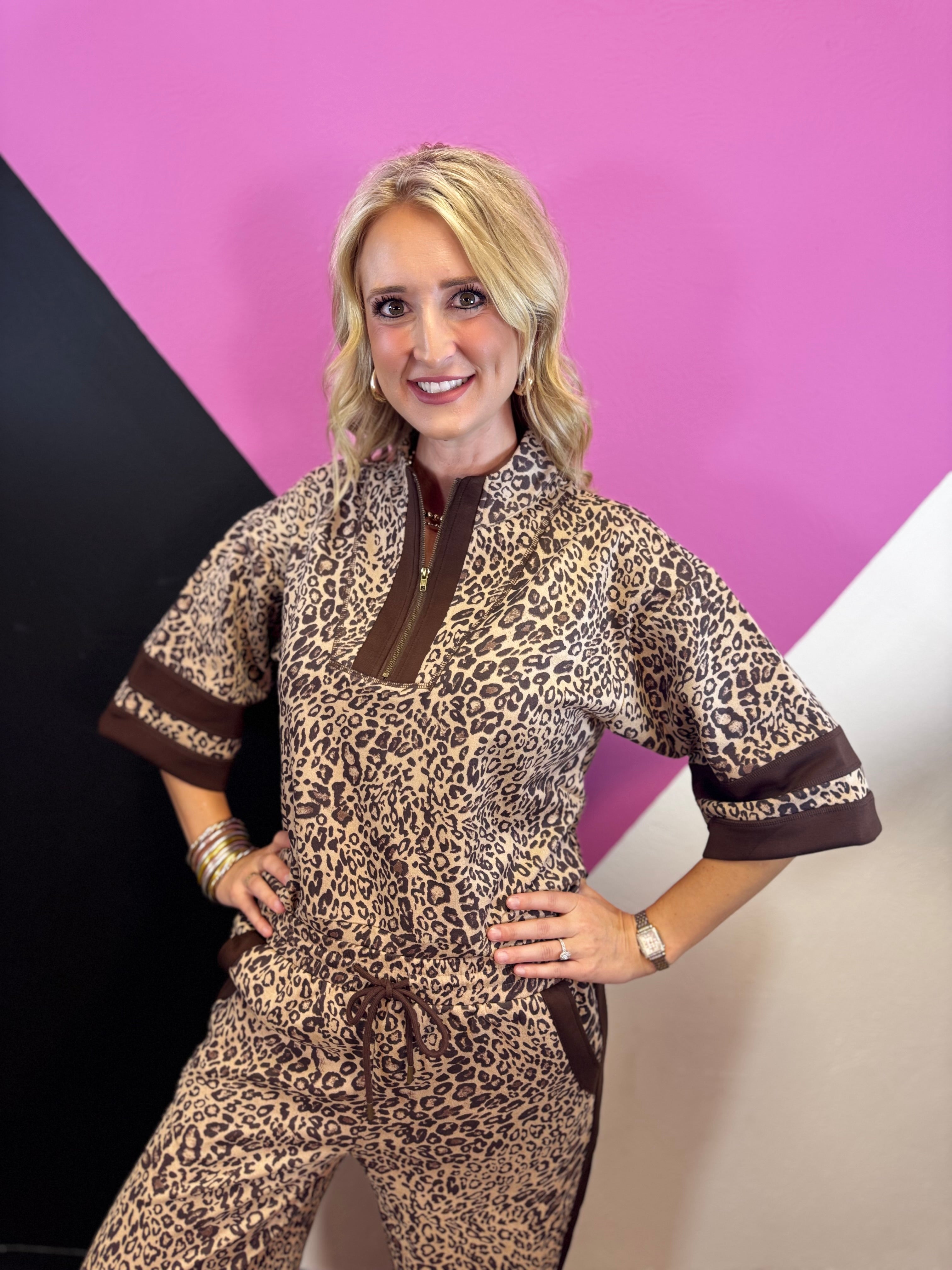 Leopard print pullover with rich brown contrast trim, zip neckline, and short wide sleeves.