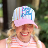 Colorful striped baseball hat with pink brim and Living the Dream embroidery.
