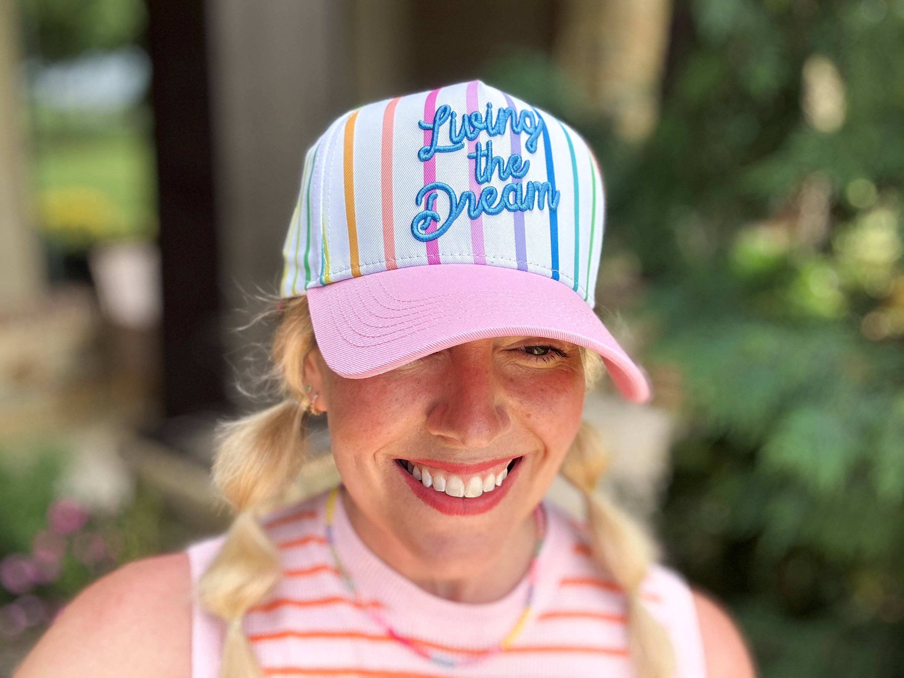 Colorful striped baseball hat with pink brim and Living the Dream embroidery.