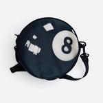 Round black 8-ball crossbody purse with adjustable strap.