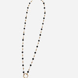 Gold chain necklace with spaced black beads and crystal-accented textured ring charm.