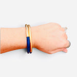 Navy enamel bracelet with textured brushed gold-tone finish and easy slip-on design.