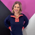 Navy half-zip pullover with vibrant pink and orange plaid neckline and cuff accents.