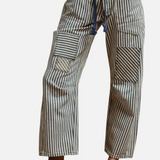 Navy striped twill barrel pants with rope tie, decorative pockets, and relaxed cotton fit.