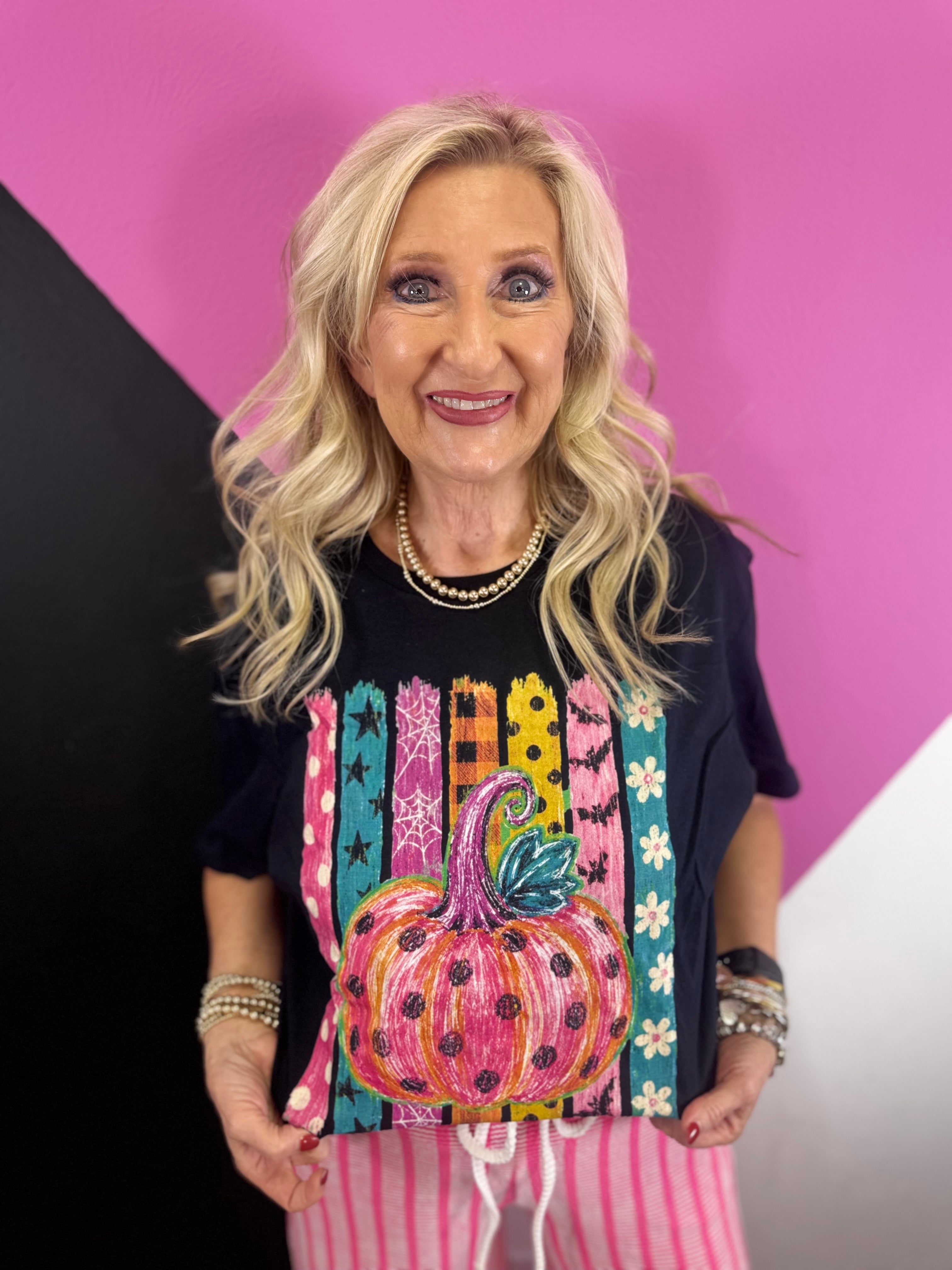 Black tee with neon pink polka dot pumpkin, colorful stripes, stars and florals.