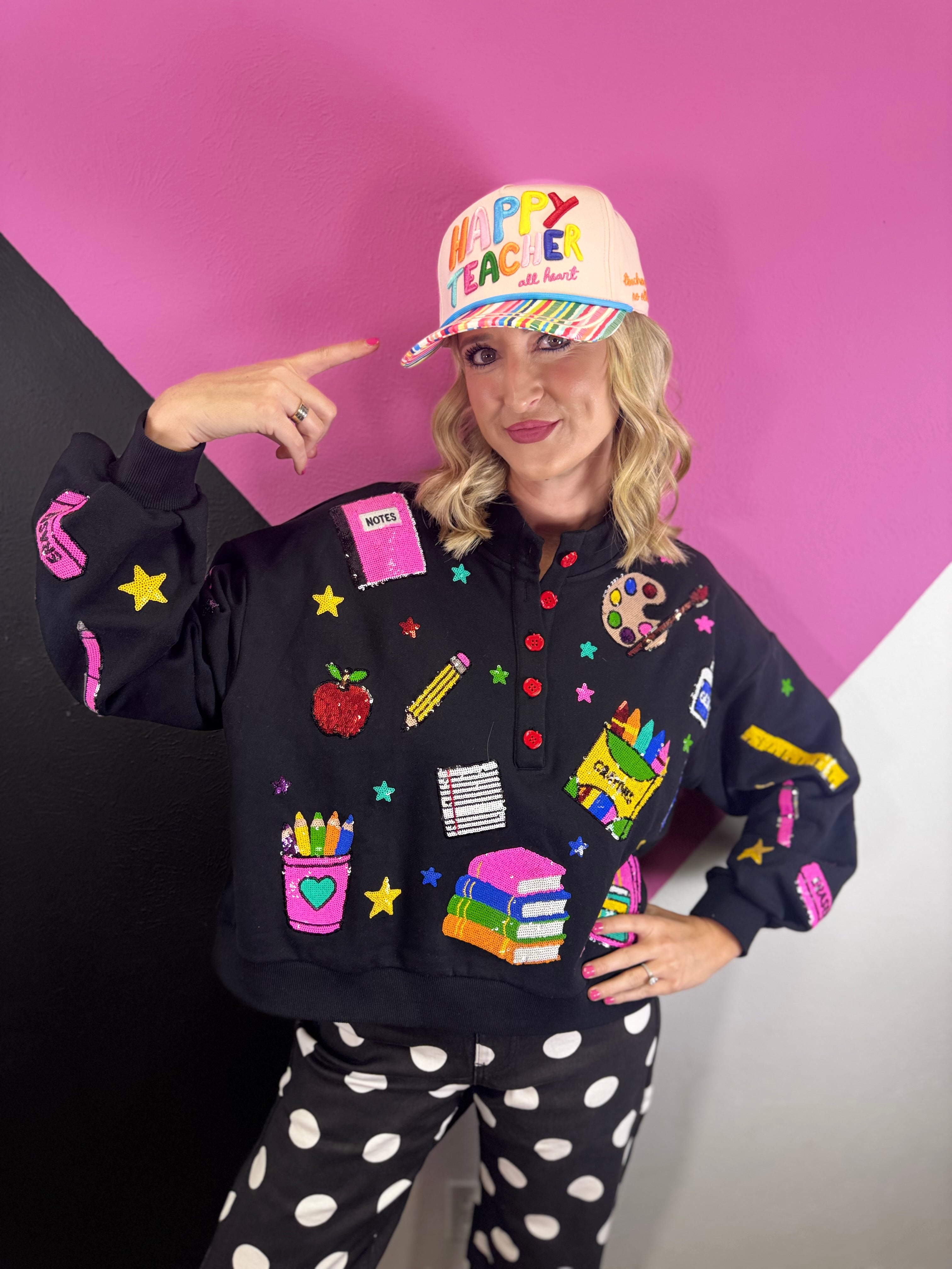 Black teacher pullover with colorful sequin school supplies, stars, and red button details.