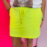 Solid skort with elastic back waistband, drawstring, built-in shorts, and side pockets.