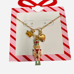 Gold necklace with pink nutcracker, gold heart, and yellow rhinestone crown charms.