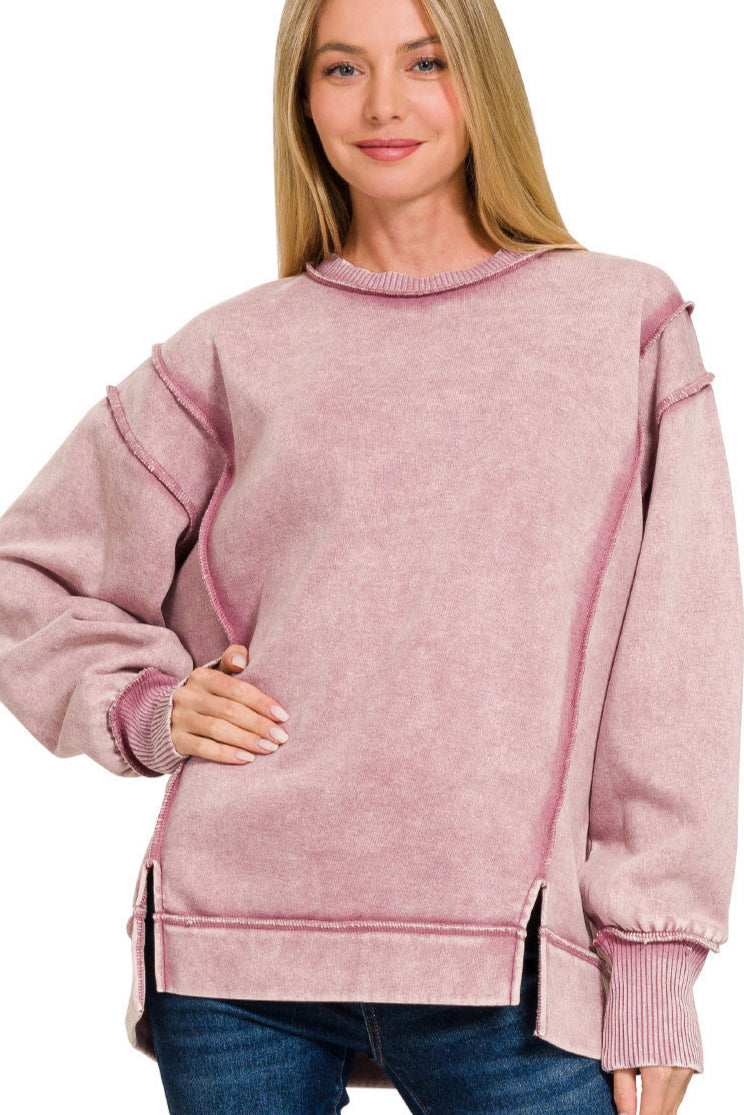 Light rose acid wash fleece sweatshirt with exposed seams and side slits.