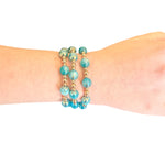Water resistant ocean blue beaded elastic bracelet with pearlescent beads and gold spacer accents.