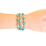 Water resistant ocean blue beaded elastic bracelet with pearlescent beads and gold spacer accents.