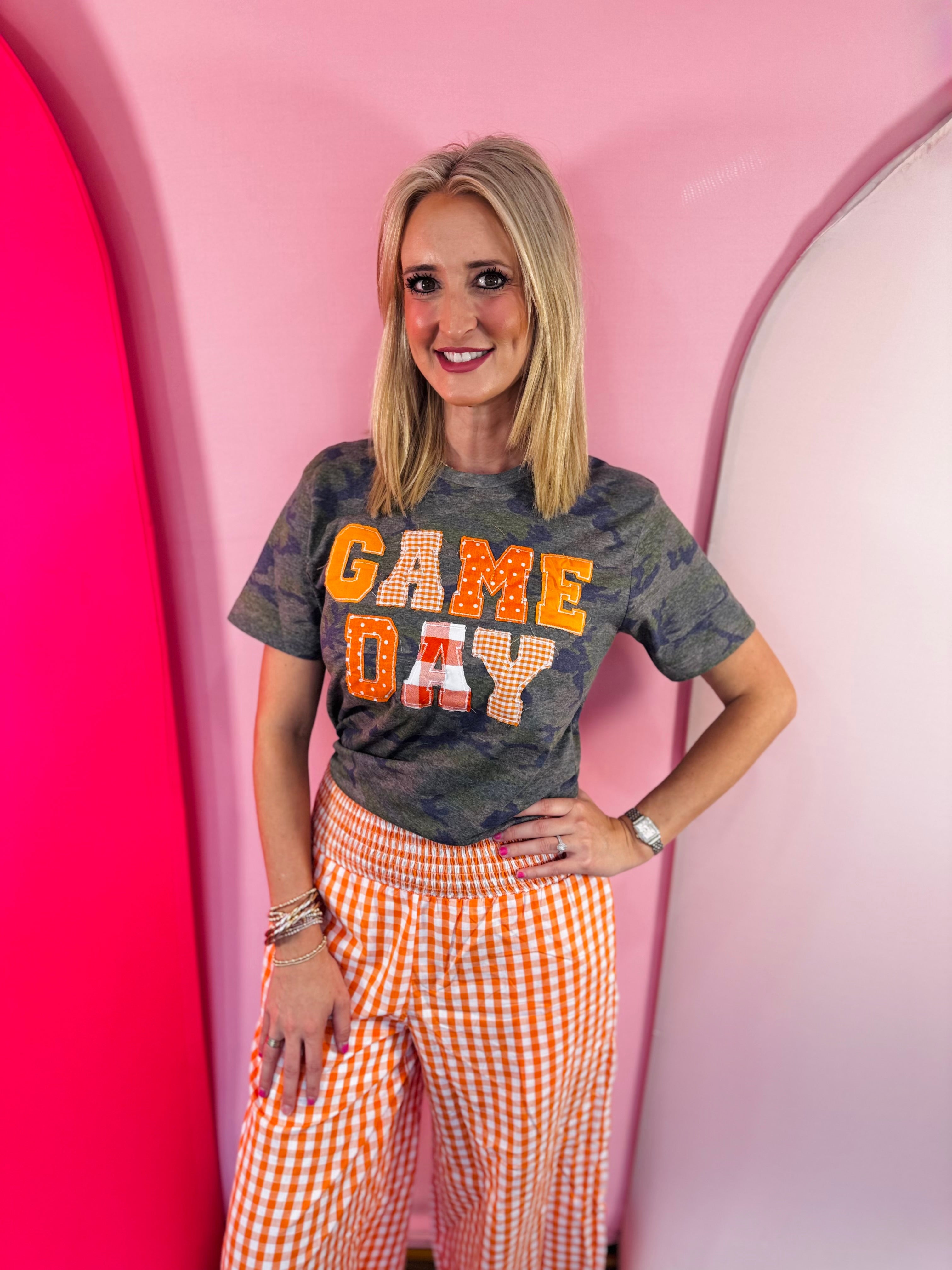 Orange Game Day tee with patchwork appliqué lettering and mixed print details.