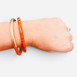 Orange enamel cuff bracelet with textured brushed gold-tone finish.