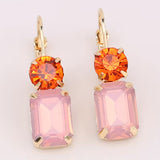 Blush pink rectangular rhinestone dangle earrings on vibrant orange circular rhinestone studs.