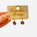 Gold hoop earrings with red and green peppermint swirl enamel charms.