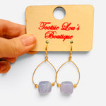 Periwinkle marbled bead earrings with gold-tone teardrop frames and gold accents.