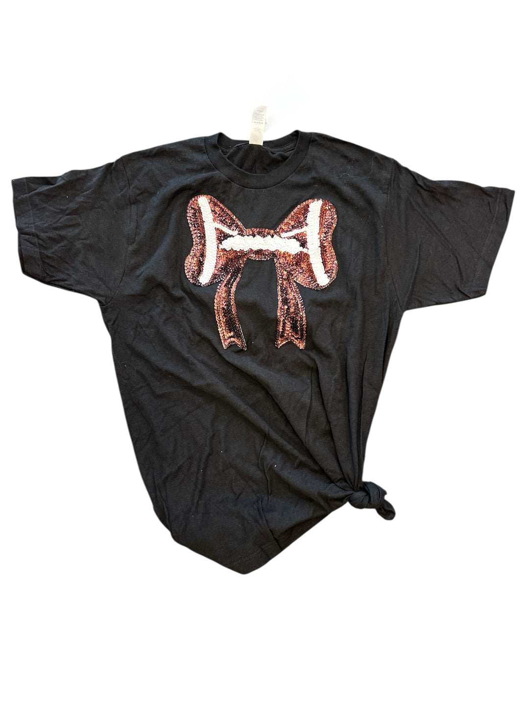 Black t-shirt with a sequin football and bow design on the front, laid flat to show sparkle and style.