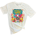 Flat lay of the Vaya Con Dios Tee on a plain surface, displaying the colorful floral print and rhinestone embellishments on the front.