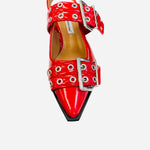 Red pointed-toe flats with bold silver double buckle straps and a slingback backstrap, combining vibrant color with edgy charm.