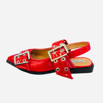 Red pointed-toe flats with bold silver double buckle straps and a slingback backstrap, combining vibrant color with edgy charm.