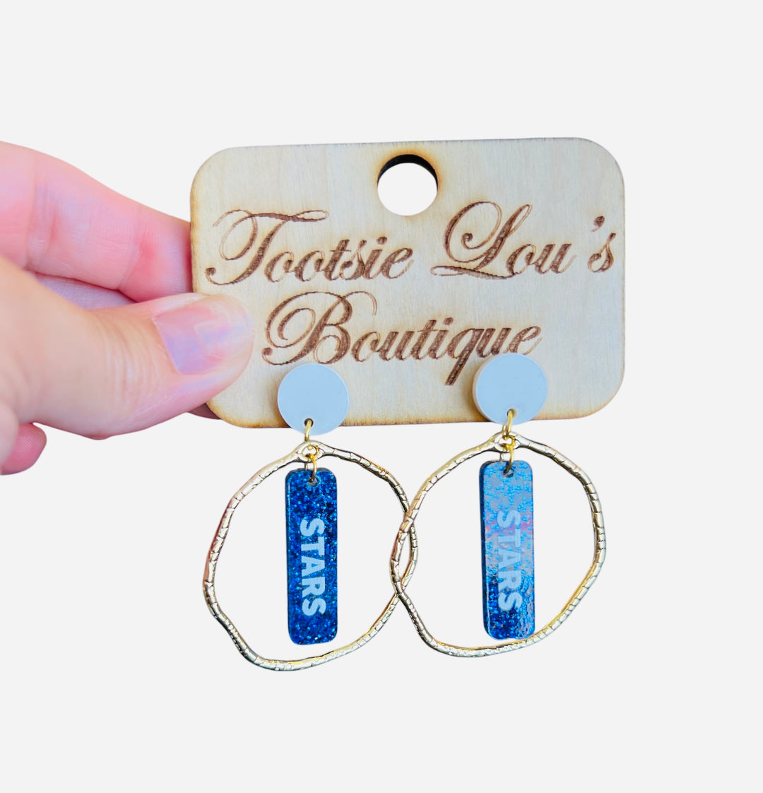 Glittery blue dangle earrings with white STARS lettering, white stud, and gold circle frame—perfect for bold game day spirit.