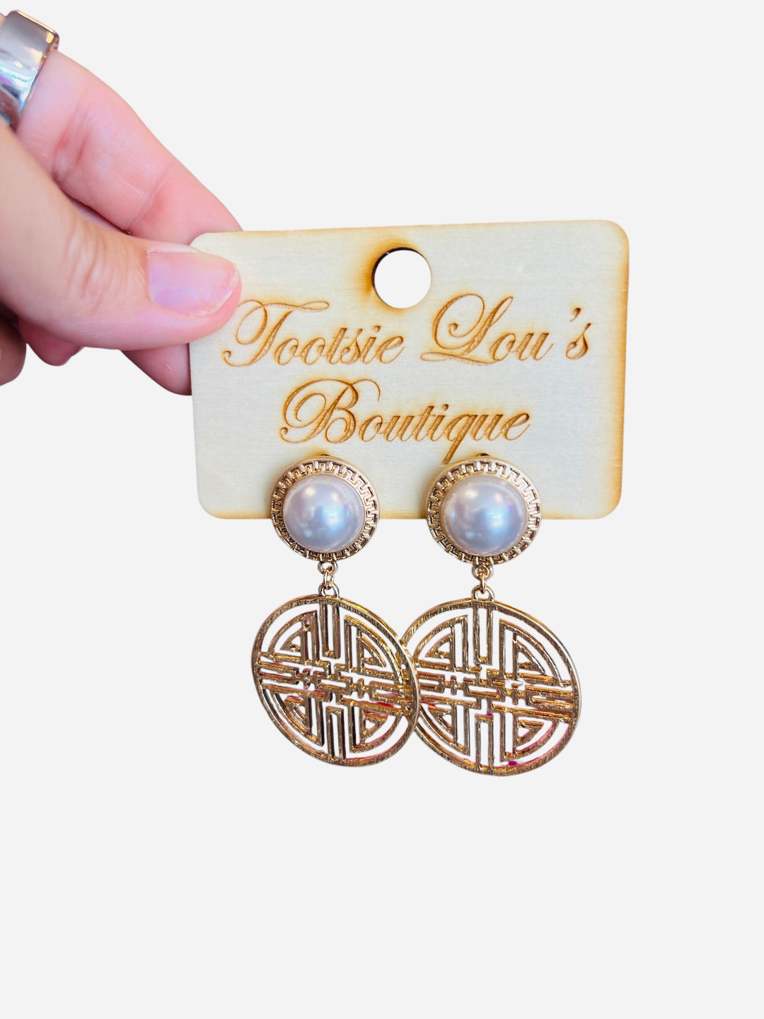 A pair of earrings featuring a central white pearl stud surrounded by a circular, textured gold medallion.
