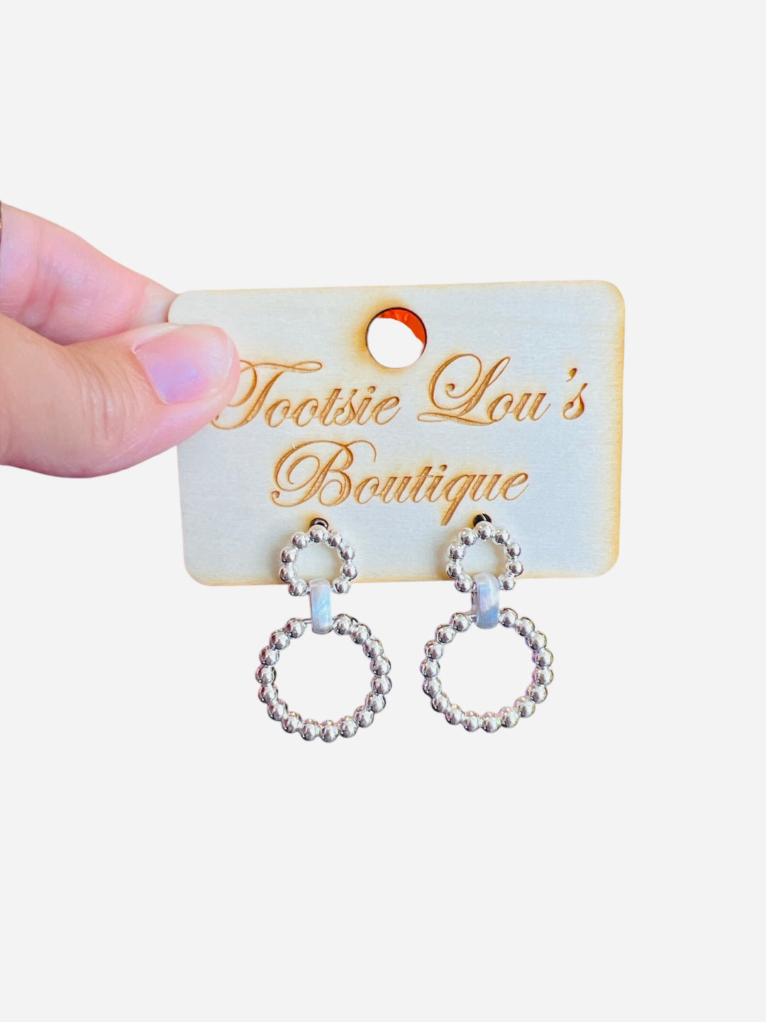 A pair of silver earrings, each featuring two interlinked hoops. Both hoops are adorned with a detailed, textured beaded pattern.