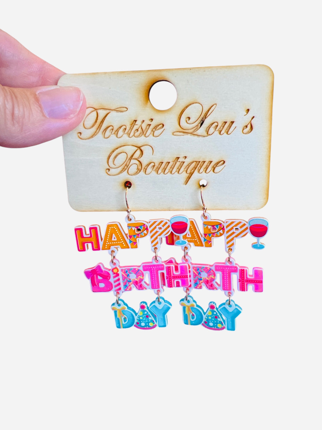 A pair of playful dangle earrings featuring colorful charms, including letter beads that spell out "Happy Birthday," a miniature party hat, and a small wine glass.