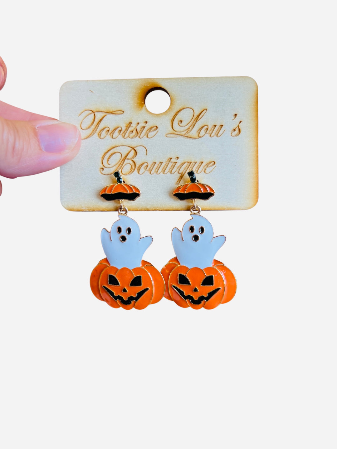A pair of dangle earrings, each featuring a white cartoon ghost playfully popping out of the top of a carved orange jack-o'-lantern.