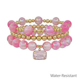 Pink beaded stretch bracelets with gold accents and square crystal charm, water resistant and lead safe.