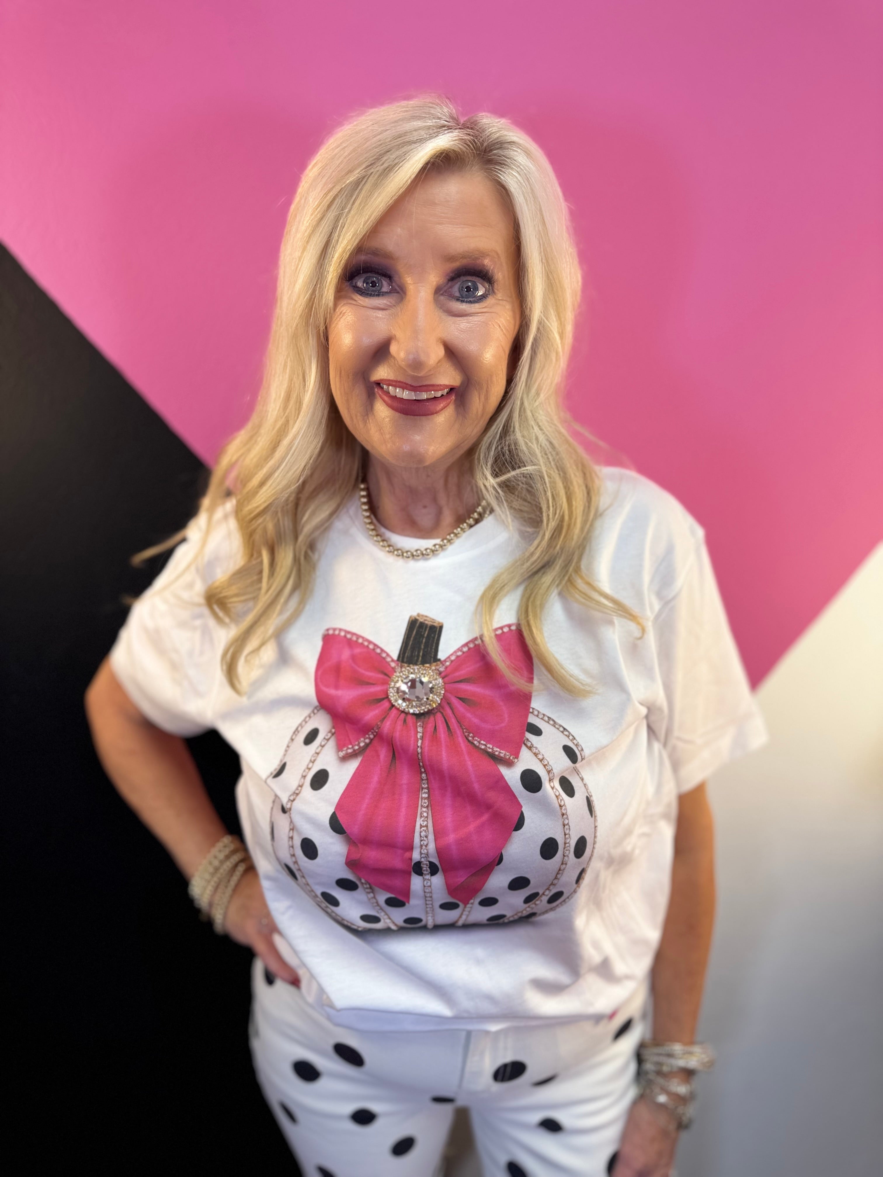 White tee with polka dot pumpkin, sparkling trim, oversized pink bow, and jeweled center.
