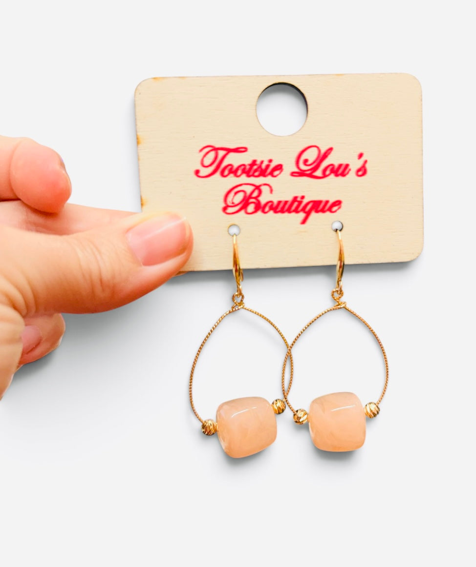 Pink marbled bead earrings with gold-tone teardrop frames and gold accents.