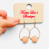 Pink marbled bead earrings with gold-tone teardrop frames and gold accents.