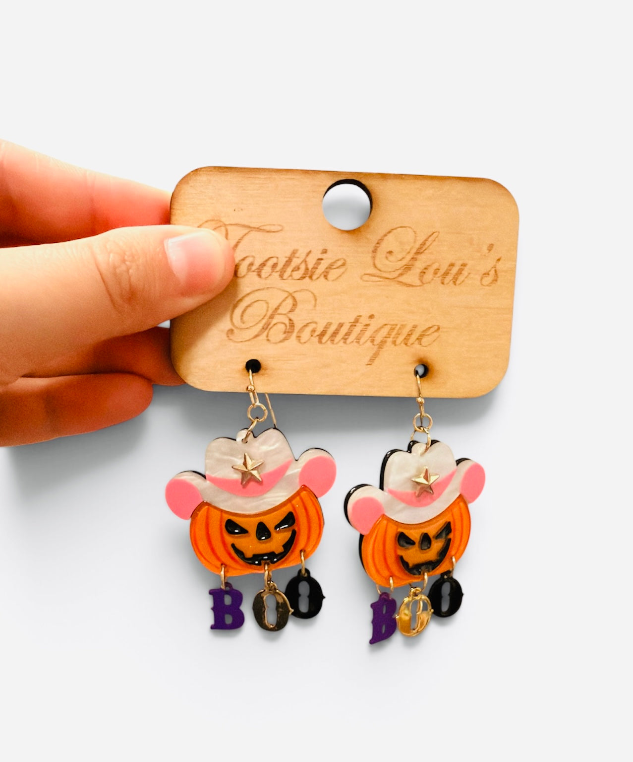 Jack-o-lantern earrings with pink cowboy hats and dangling BOO letters.