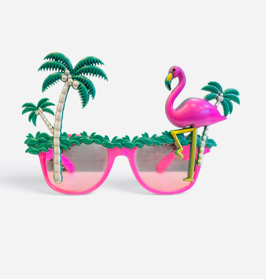 Bright pink sunglasses topped with palm trees, tropical greenery, and an oversized flamingo.