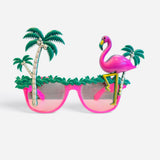 Bright pink sunglasses topped with palm trees, tropical greenery, and an oversized flamingo.