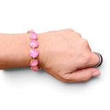 Pink opaque crystal tennis bracelet with oversized iridescent stones and gold-tone settings.