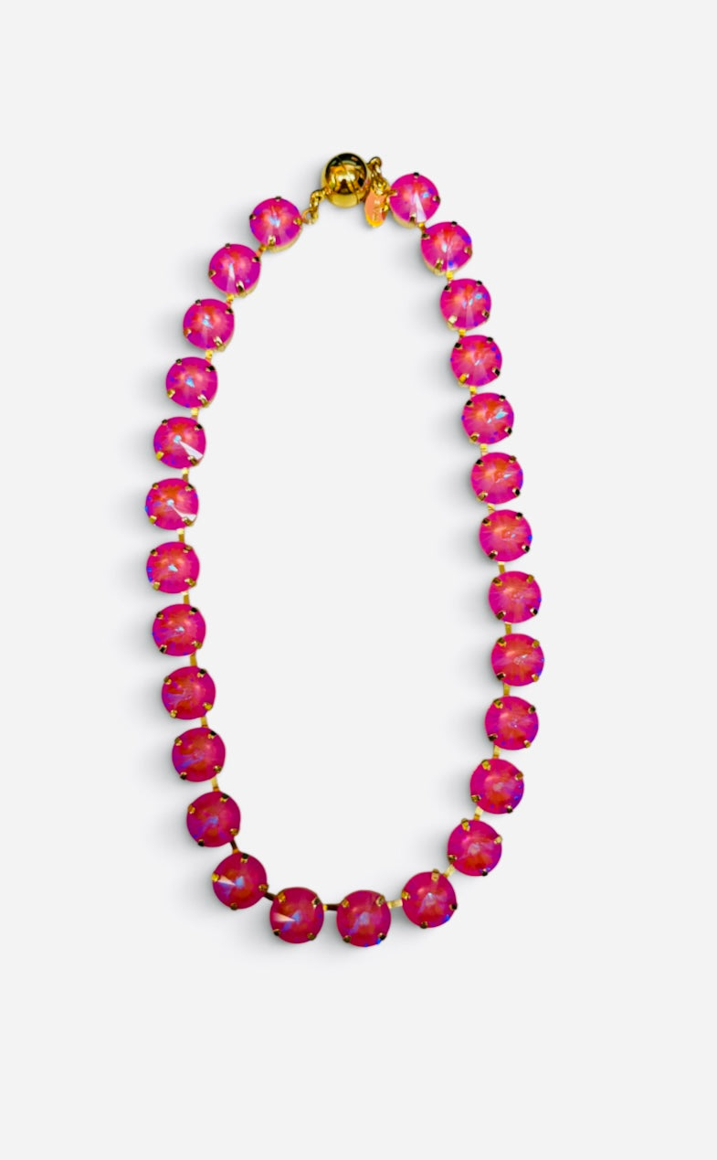 Pink opaque crystal tennis necklace with iridescent stones, gold-tone settings, and magnetic clasp.