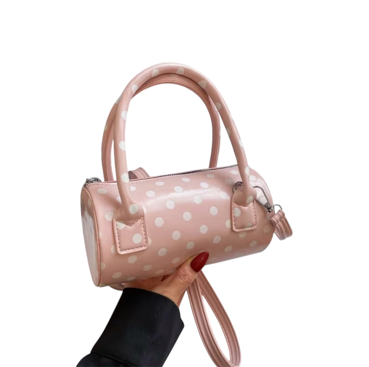 Pink polka dot crossbody bag with adjustable strap and top handles.