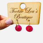 Gold hoop earrings with glossy pink drop charms for a bold, playful statement look.