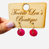 Gold hoop earrings with glossy pink drop charms for a bold, playful statement look.