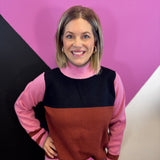 Pink, rust, and black colorblock sweater with mock neck, long sleeves, and striped cuffs.