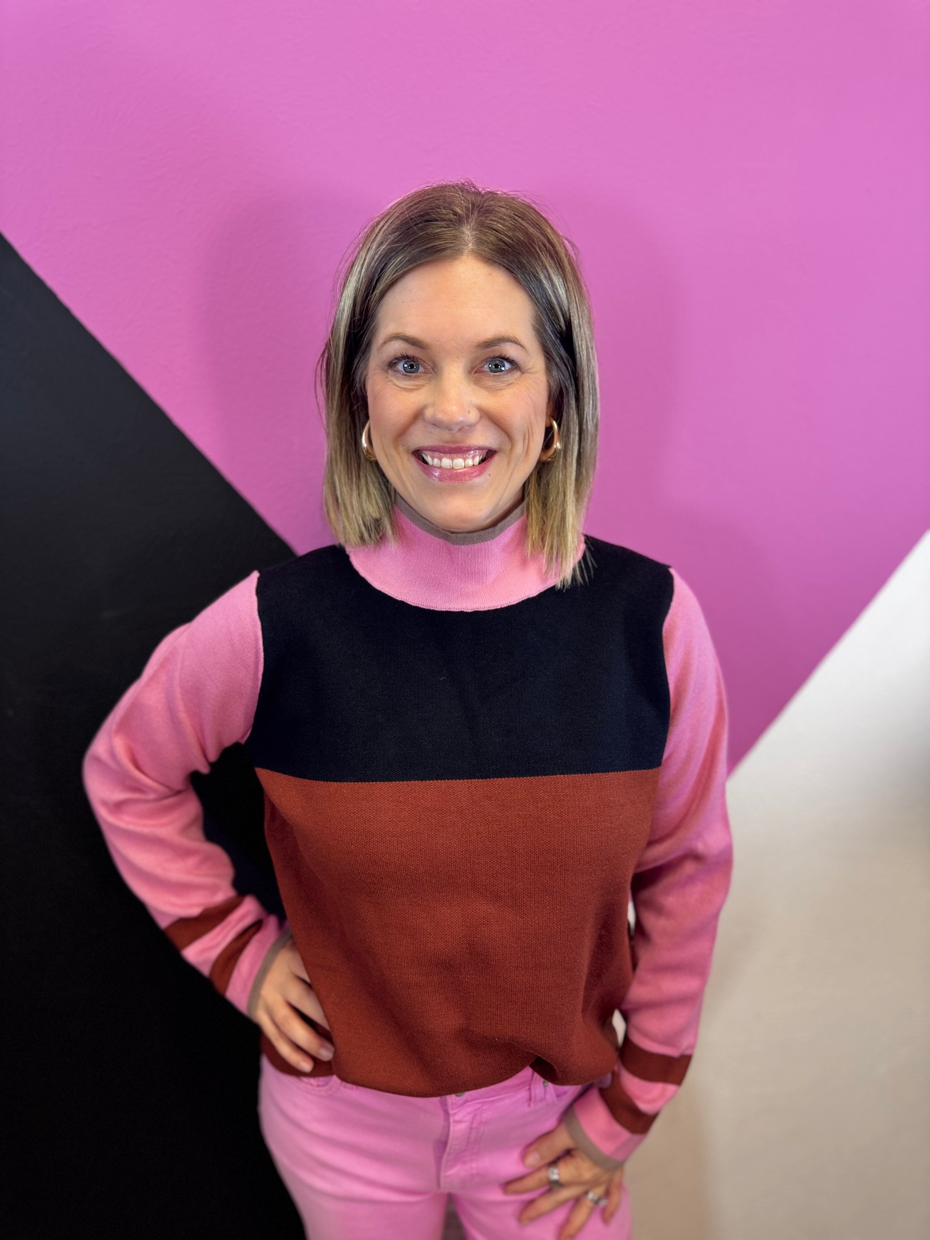 Pink, rust, and black colorblock sweater with mock neck, long sleeves, and striped cuffs.