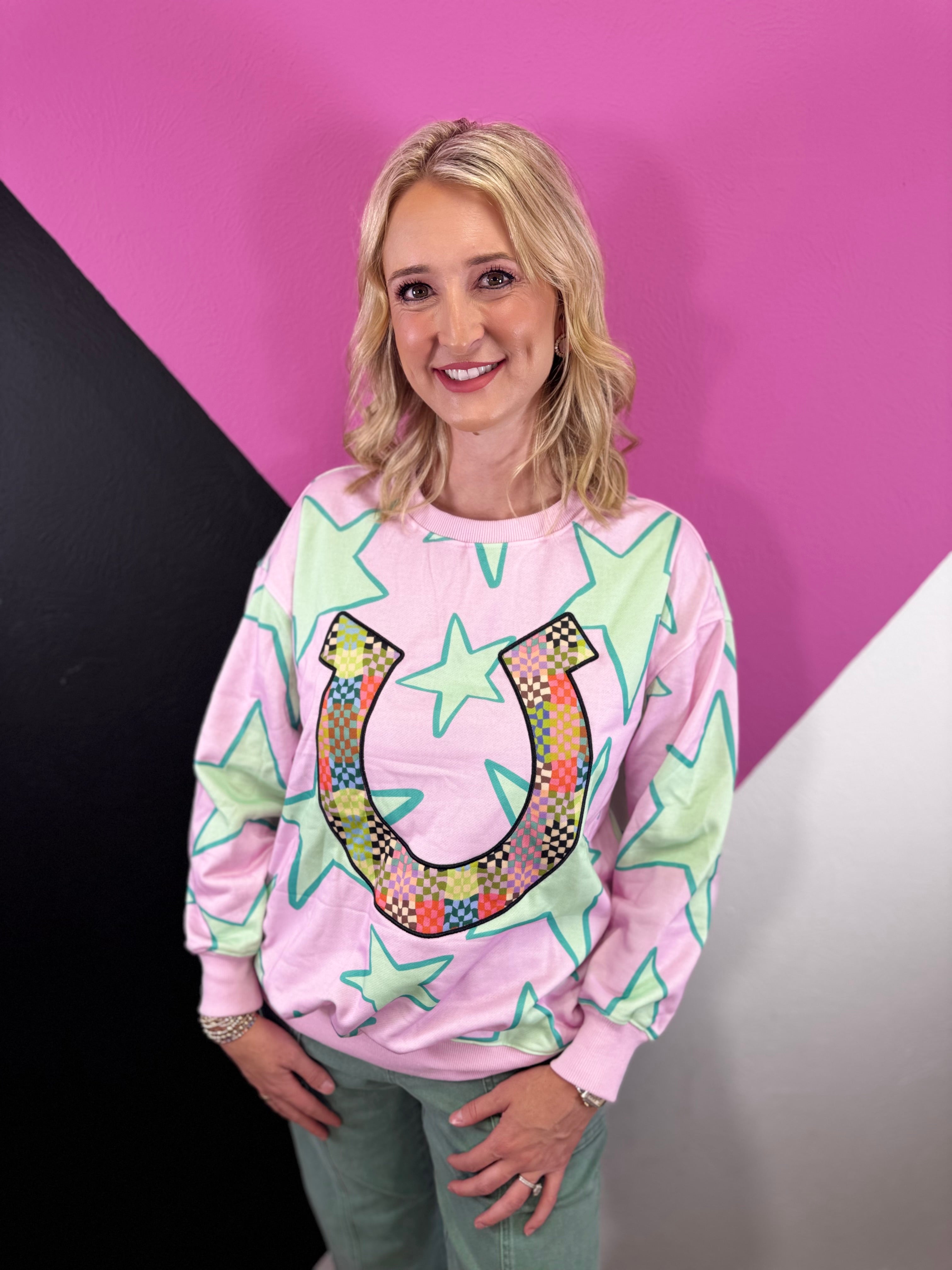 Pink pullover with turquoise stars and colorful patchwork horseshoe graphic.