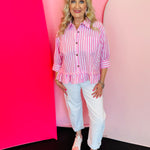 Pink and white striped oversized blouse with button front, chest pocket, and asymmetrical ruffle hem