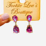 Gold-tone earrings with two stacked faceted pink teardrop crystals.